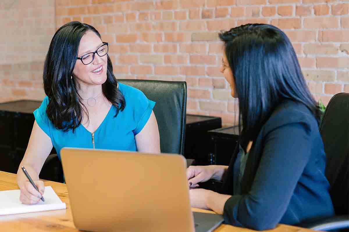 phone, fintech notebook, and coffee cup on table, with a hand over the notebook with a pen.
