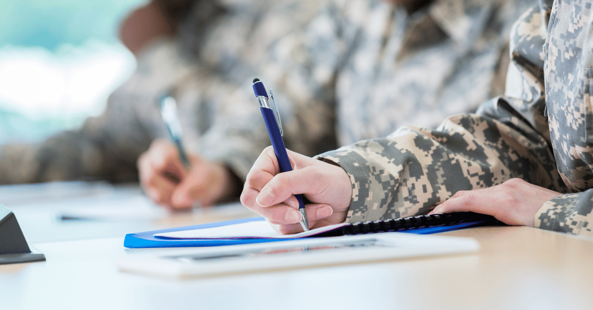 phone, fintech notebook, and coffee cup on table, with a hand over the notebook with a pen.
